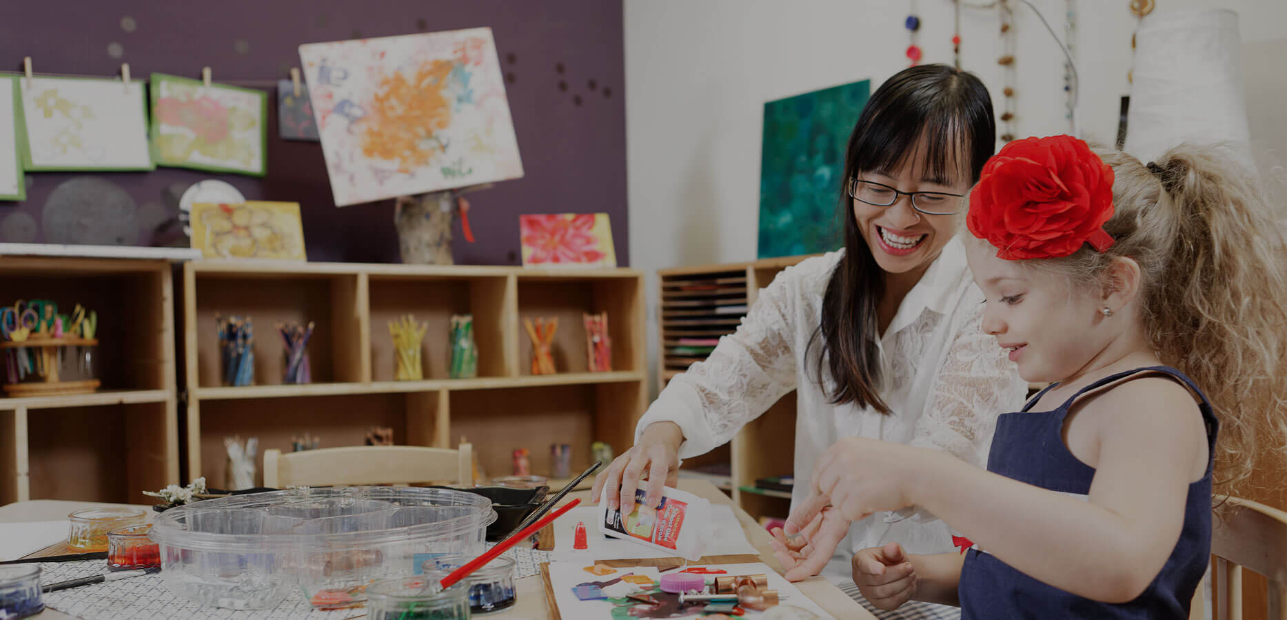 Child care worker painting with young girl