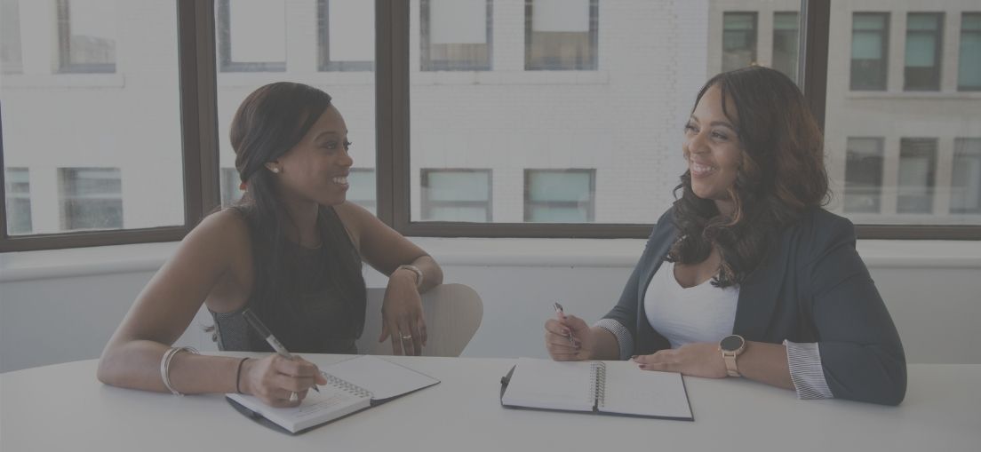 Two women at a table planning with notebooks