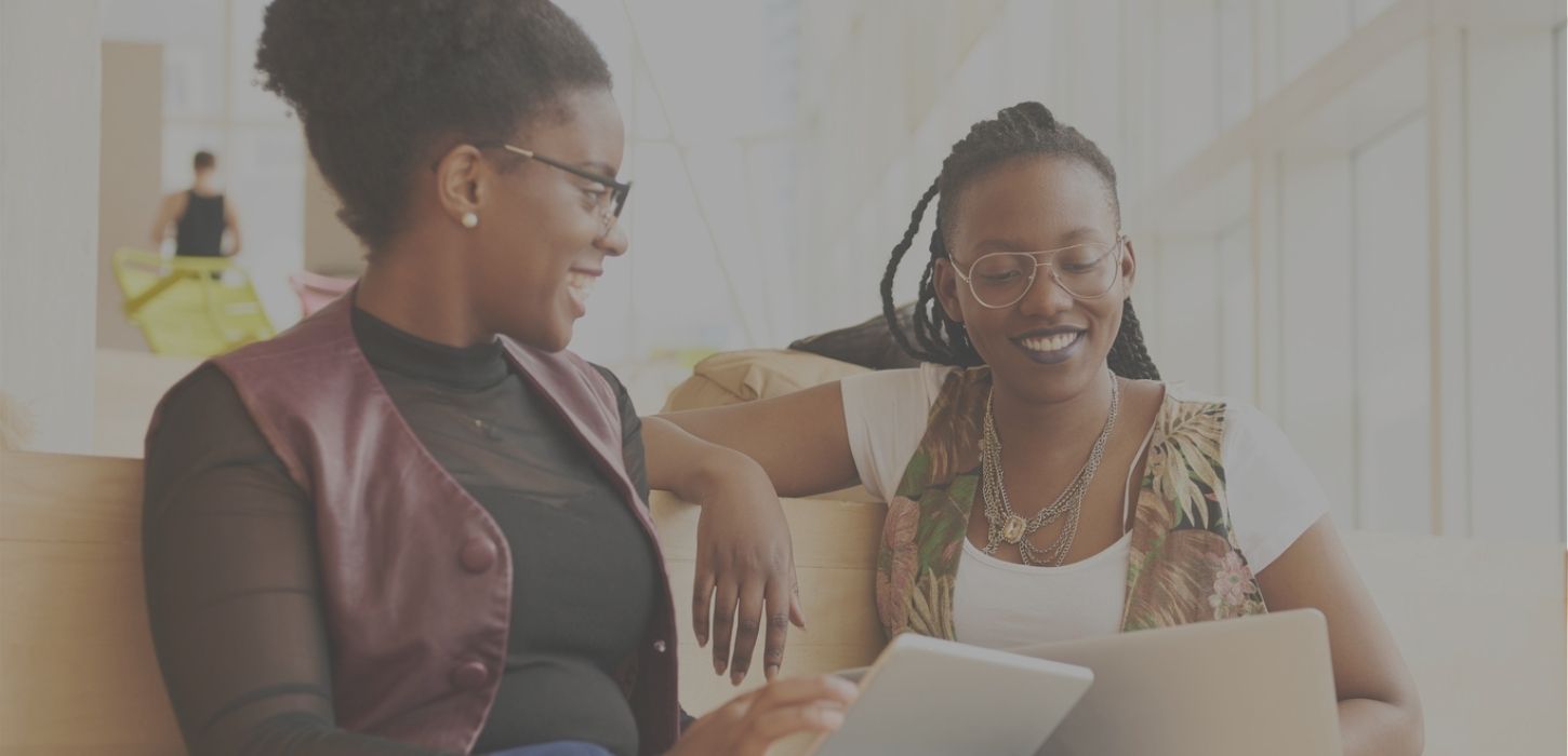 Two women looking at tablets and smiling, learning, education