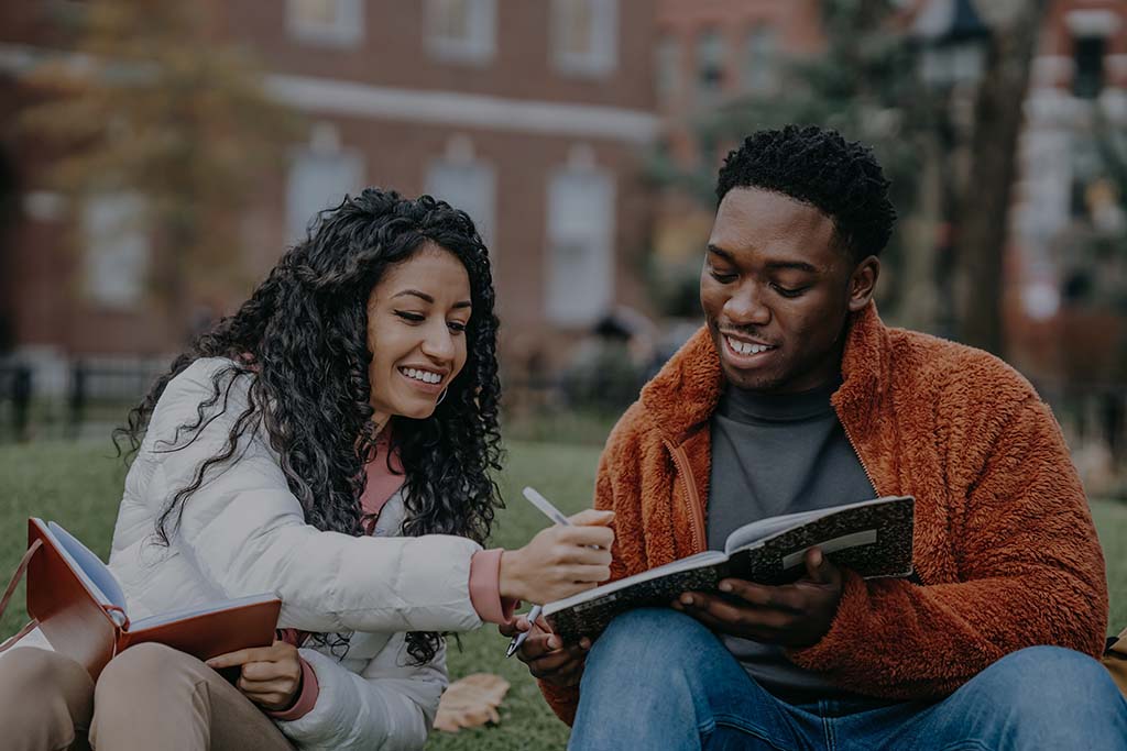 Two college students working together, smiling, on campus